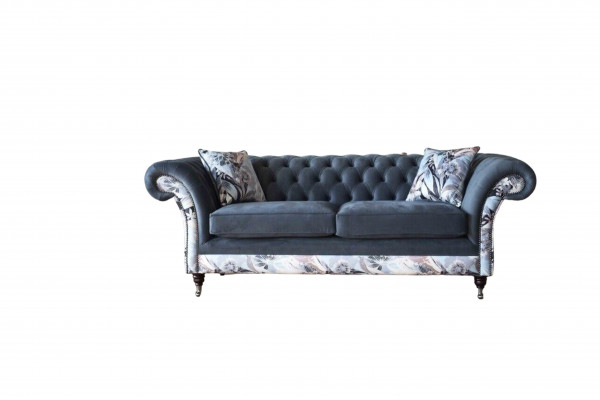 E e markant Dräisëtzer-Sofa am Chesterfield-Design mat delikaten groblommenden Dekoratioun.