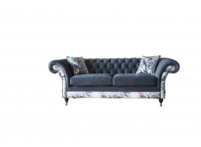 E e markant Dräisëtzer-Sofa am Chesterfield-Design mat delikaten groblommenden Dekoratioun.