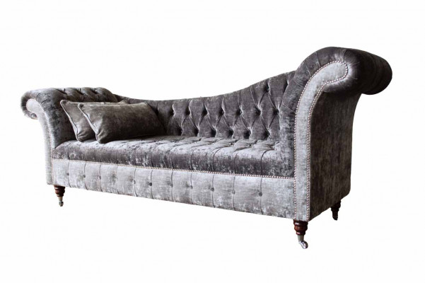 E bëqueemt, klassescht Sofa am Chesterfield-Stil an engem déif Sëlwertéin.