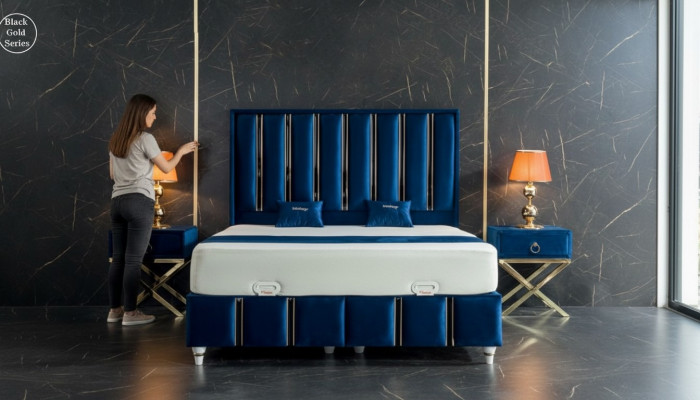 Saphirblo Bett vum Designer mat Nuetsdëscher op vergëllten Stolbeen.