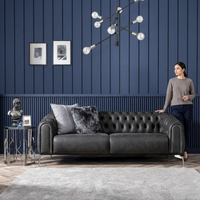 Schwaarzt riicht Viersëtzer-Sofa am Chesterfield-Stil fir de Living.