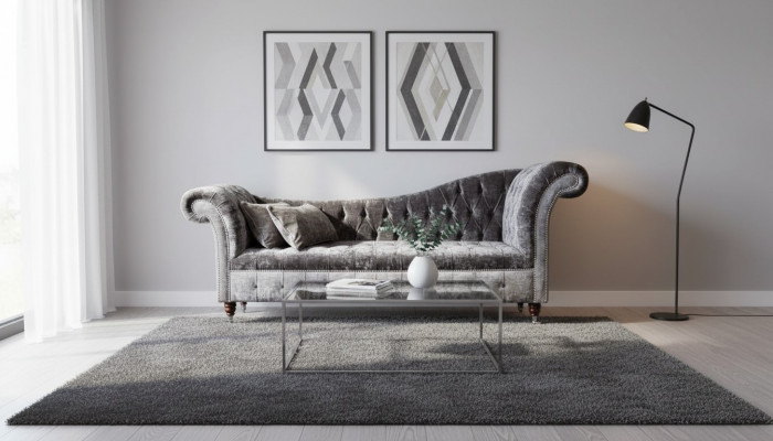 E bëqueemt, klassescht Sofa am Chesterfield-Stil an engem déif Sëlwertéin.