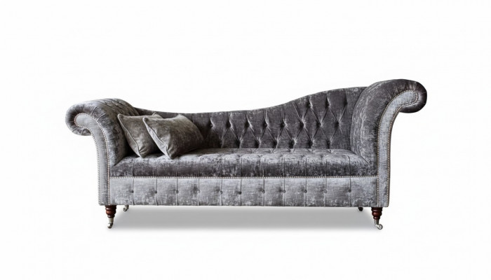 E bëqueemt, klassescht Sofa am Chesterfield-Stil an engem déif Sëlwertéin.