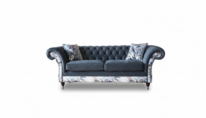 E e markant Dräisëtzer-Sofa am Chesterfield-Design mat delikaten groblommenden Dekoratioun.